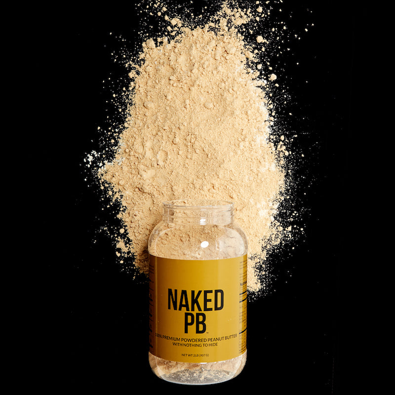 Naked PB product image with a tub of the product lying on it's side with loose peanut butter powder around it