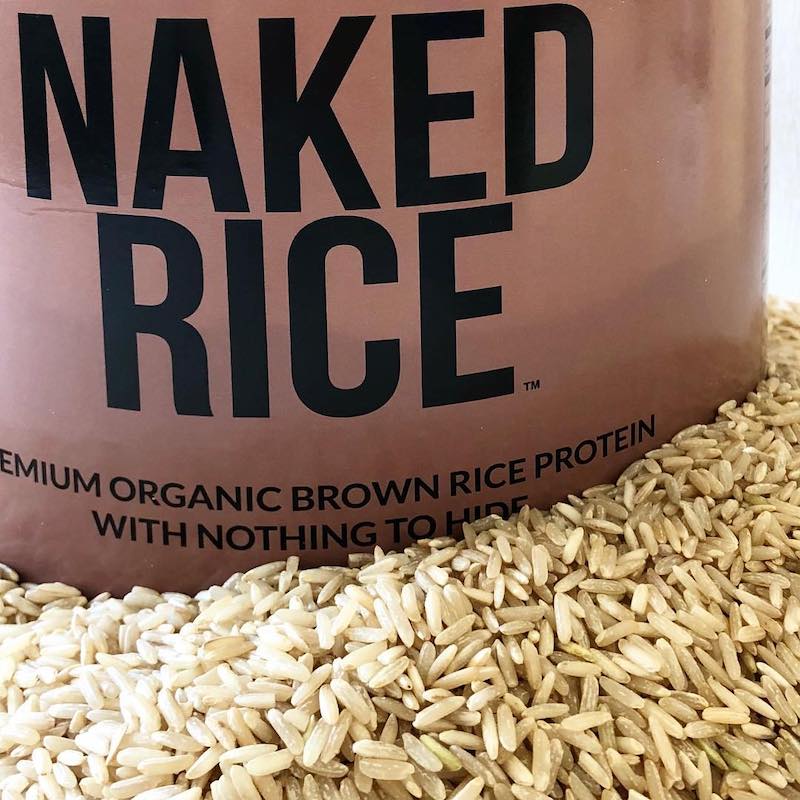 Closeup photo of a tub of Naked Rice, in a pile of raw rice