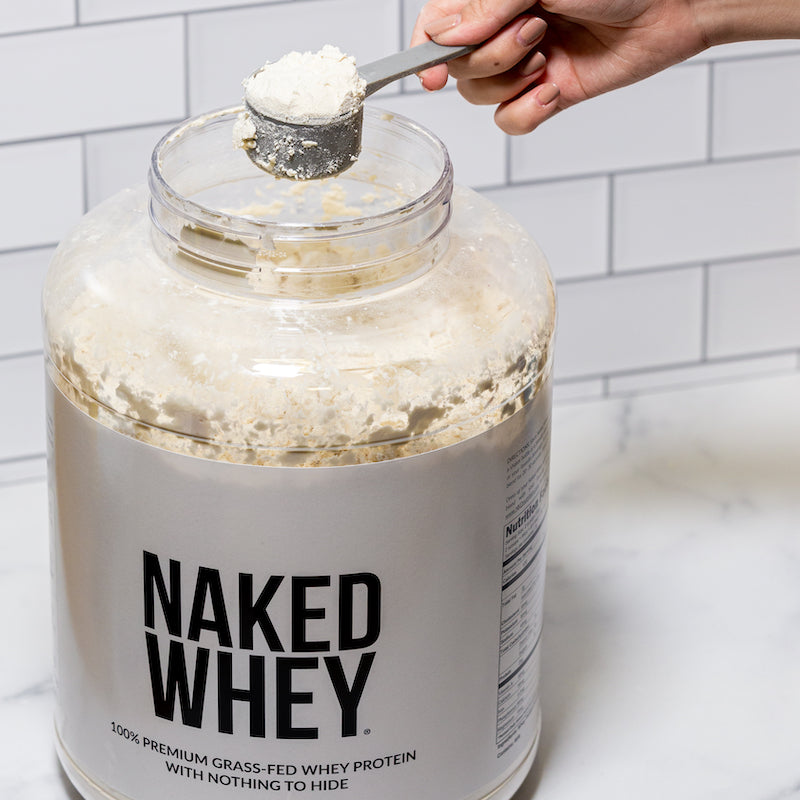 Naked Whey image with a hand scooping powder out of the tub