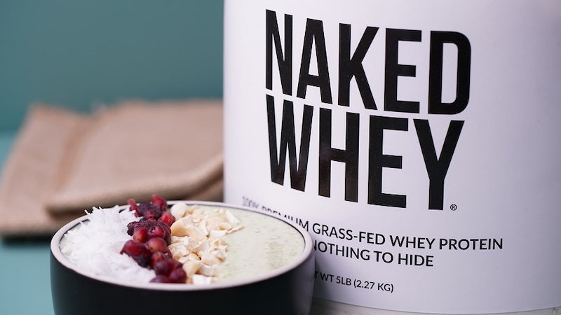 Tub of Naked Whey next to a protein smoothie bowl