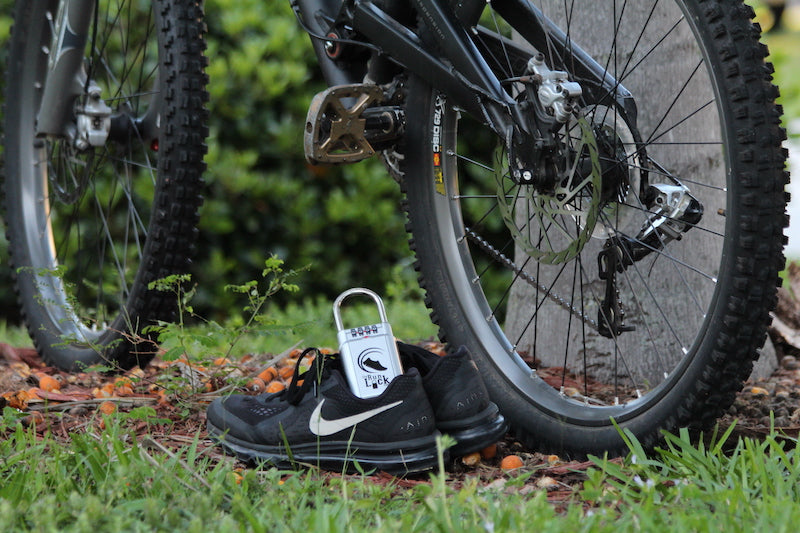 Image of a pair of running shoes next to a bicycle, with the Run Lock in one of the shoes