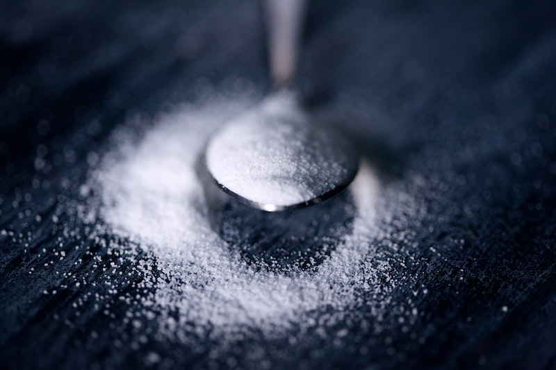 Sugar in a spoon against a wooden background