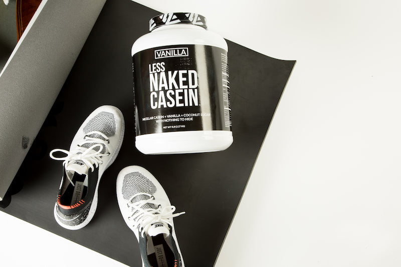 Vanilla Naked Casein on a gym mat next to a pair of gym shoes