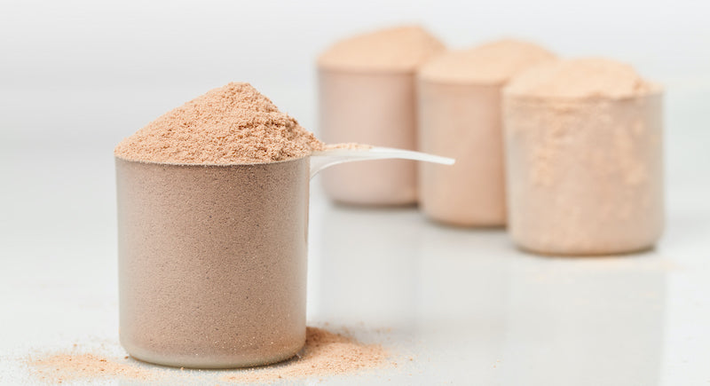 Numerous scoops of protein powder on a marble surface