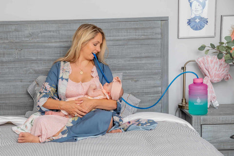 Mom breastfeeding her daughter while drinking water from the best bedside water bottle