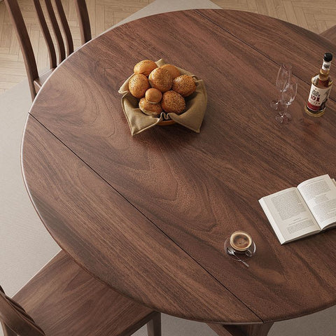 圆形木桌，摆放着休闲的用餐环境，包括新鲜出炉的面包和一本书，体现了经济实惠和舒适的室内装饰