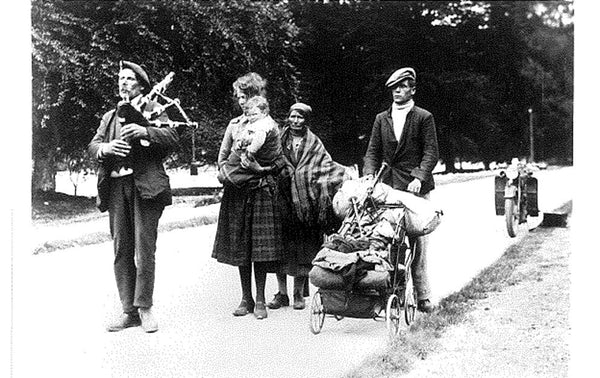 Scottish people walking in a procession with kilt, child in plaid, man playing bagpipes