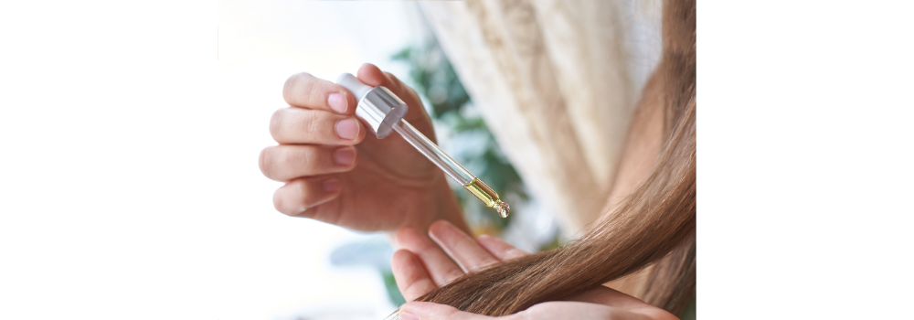 a girl applying hair oil to her hair