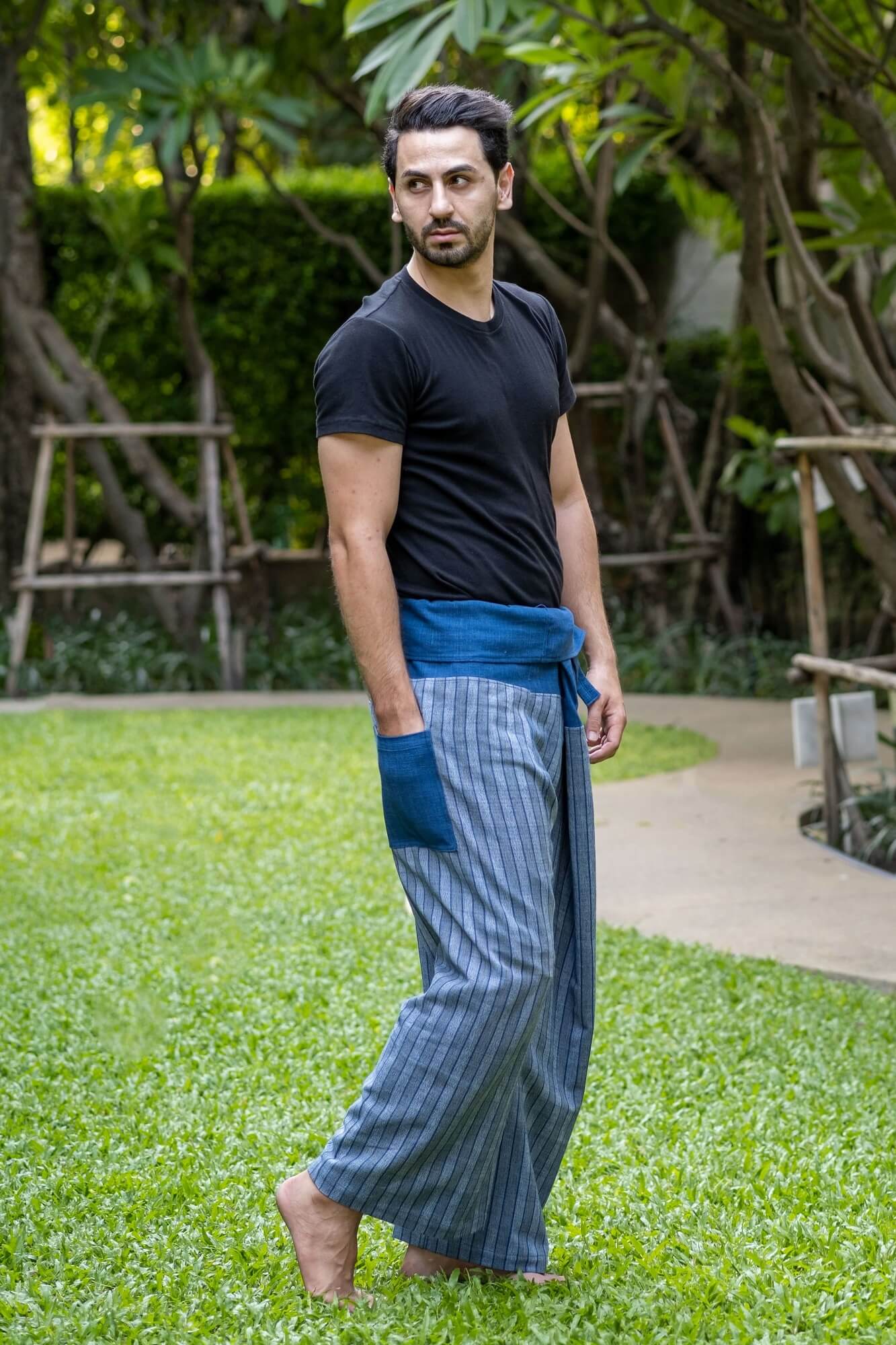 homem de pé em campo usando blusa preta e calça pescador premium azul listrada