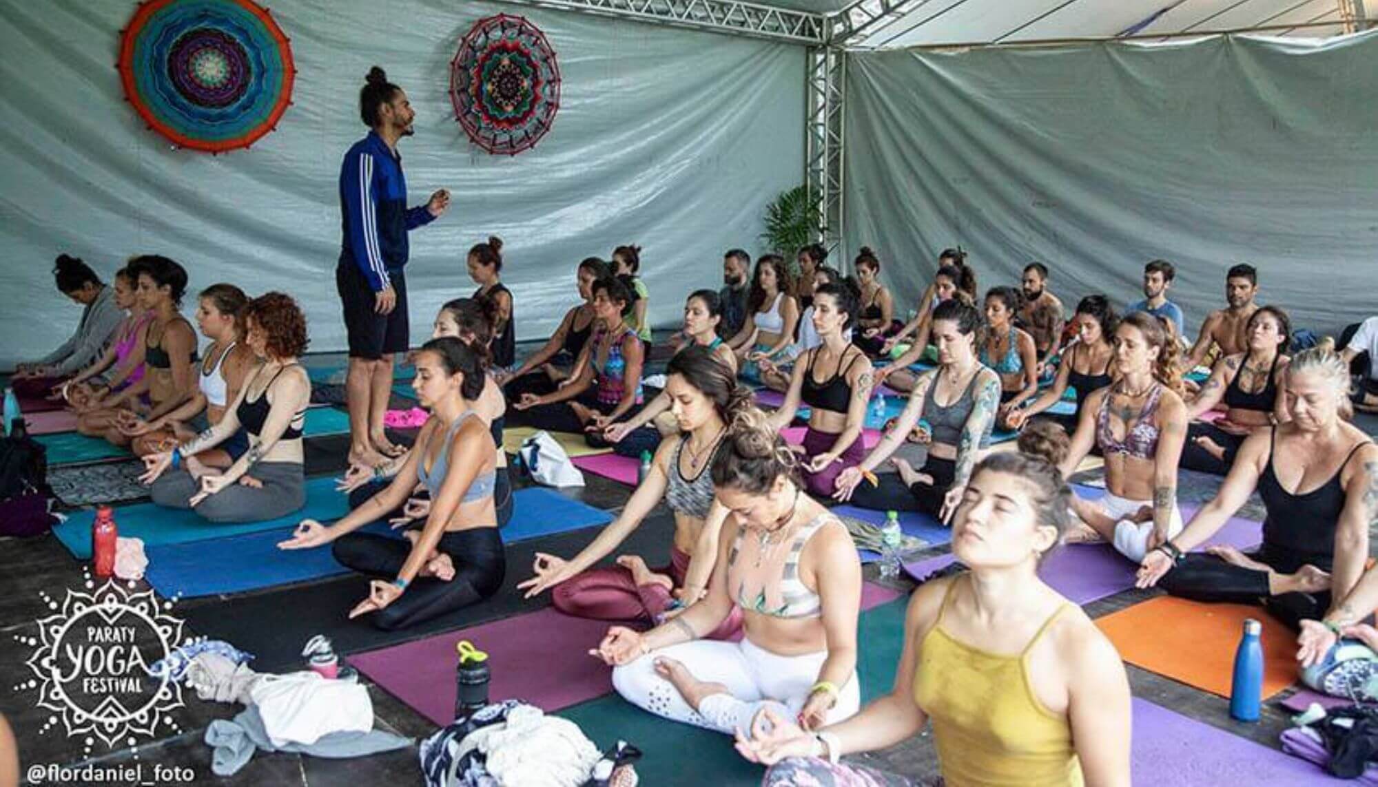 Pessoas sentadas de olhos fechados praticando yoga no Paraty Yoga Festival