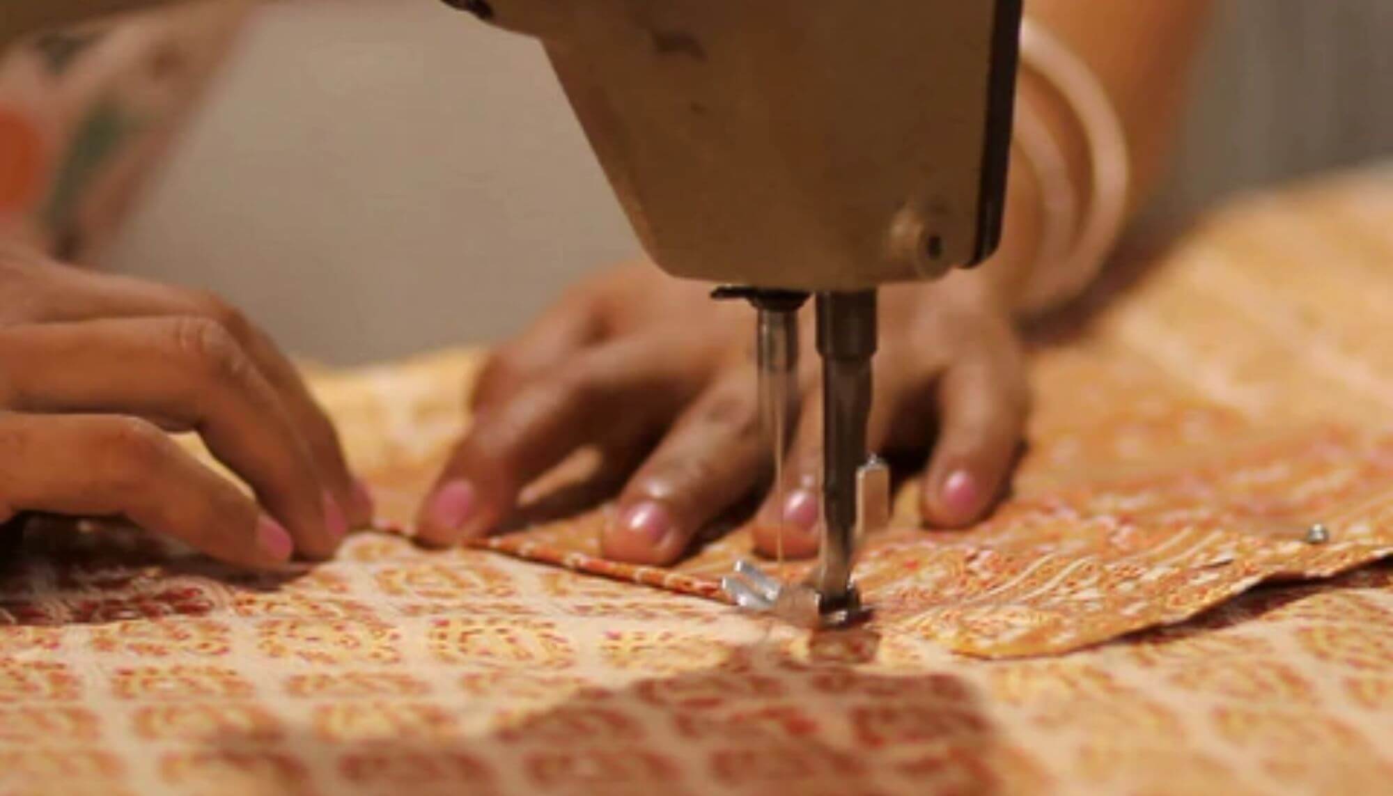 artesã tailandesa costurando na máquina uma calça thai
