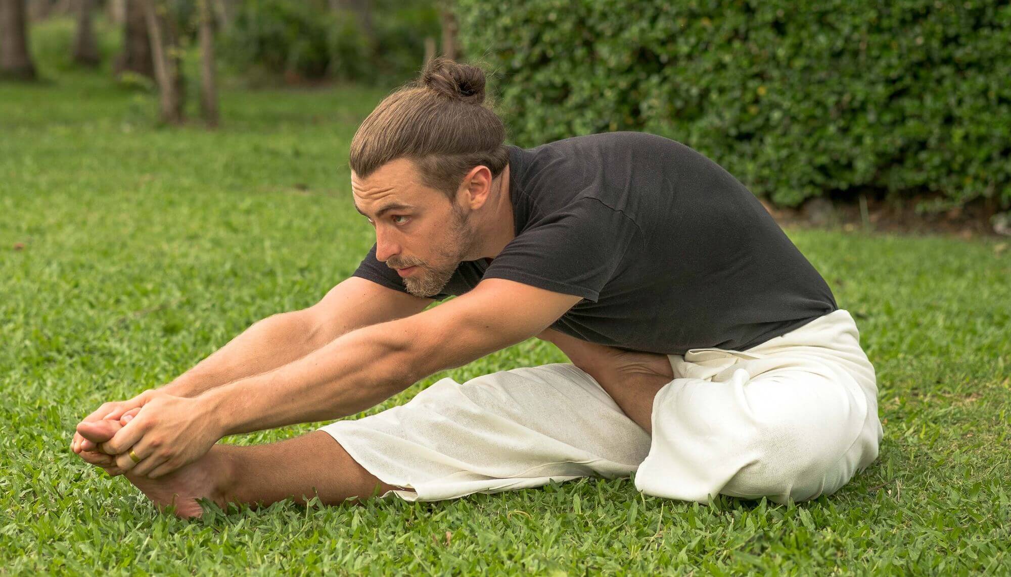 homem praticando yoga na grama vestindo calça pescador tailandesa