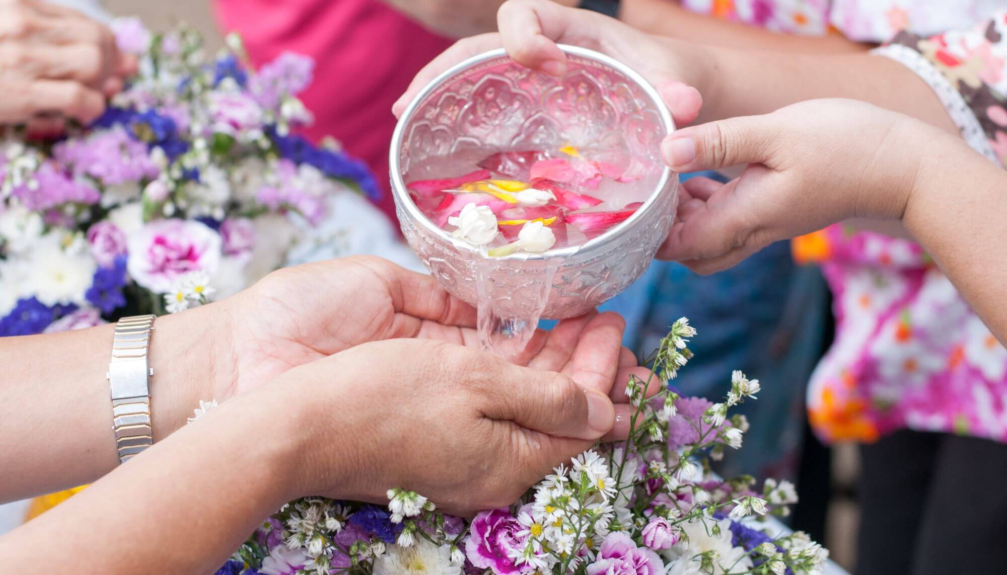 jovem derramando água com flores nas mãos de um homem adulto festival Songkran ano novo tailandes