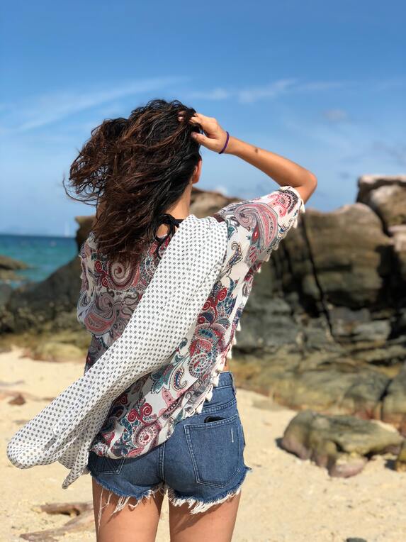 mulher de costas usando short e blusa como saída de praia