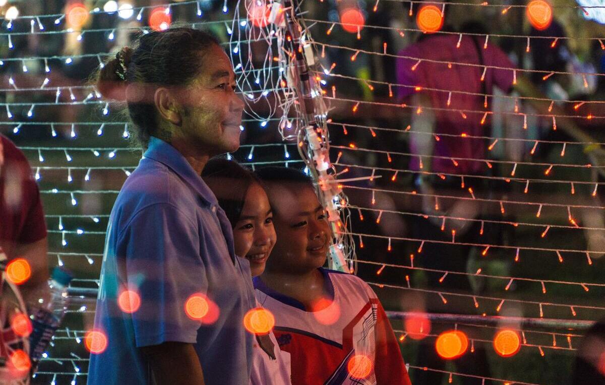 mulher e crianças rodeadas de luzes de Natal na Tailândia