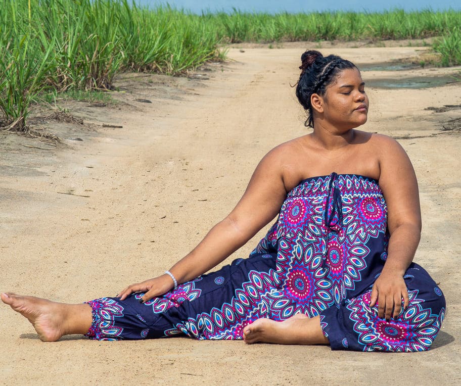 mulher sentada na areia usando macacão como calça de yoga