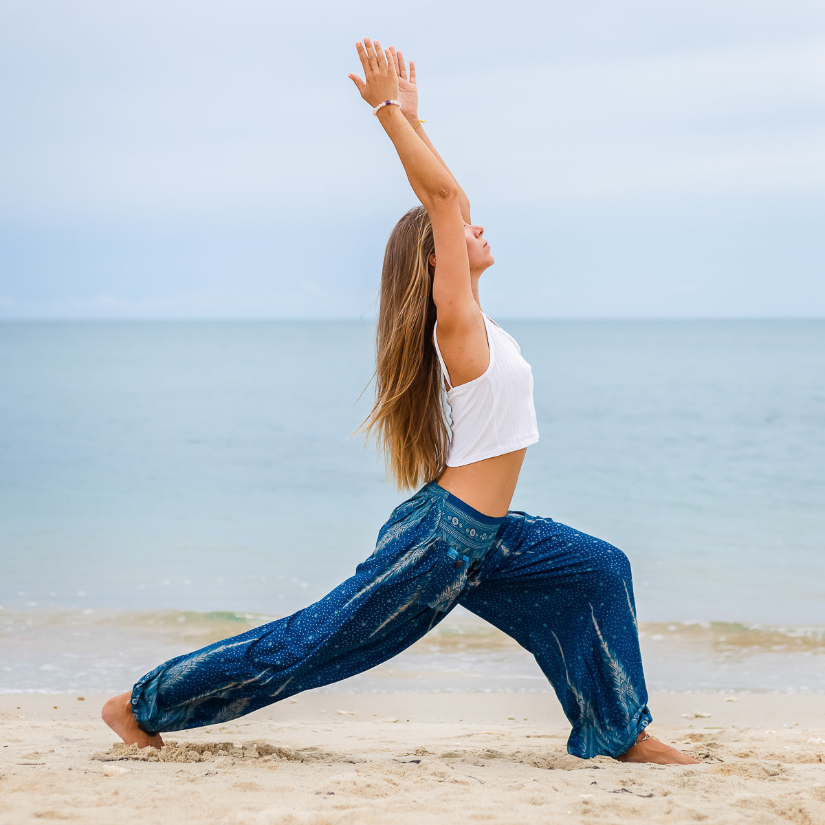 mulher de pé usando roupa vegana fazendo ioga na praia