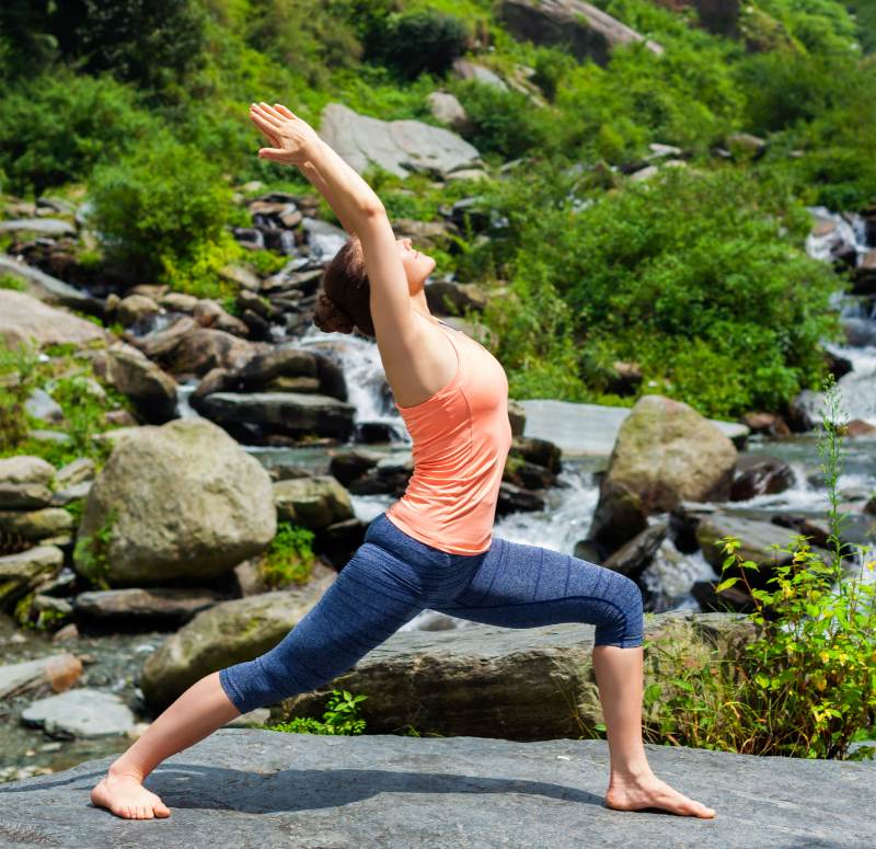 mulher fazendo postura Virabhadrasana I de Vinyasa Yoga