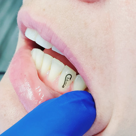 A picture of a temporary tattoo for teeth that says bite me with a fishing hook on it