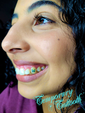 A photo of a girl with a blue butterfly temporary tooth tattoo, also known as a Temporary Tattooth.  Temporary tattoos for teeth can be applied at home or professionally for additional longevity.