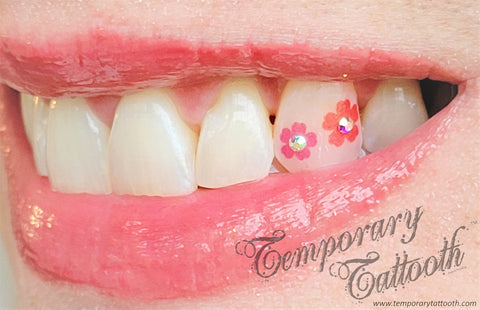 A photo of two pink flower Temporary Tattooths, or temporary tattoos for teeth that have small tooth gem crystals applied as well.