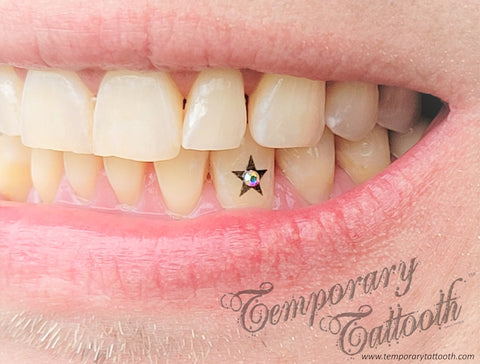 A photo of a Temporary Tattooth black star with a tooth gem in the center.  A temporary tooth tattoo that can be applied with tooth gems.