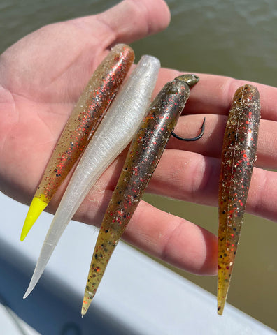 Hand holding four saltwater baits 