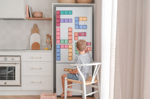 Child playing with connetix on fridge