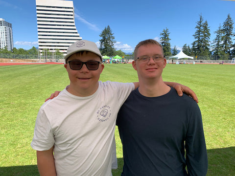 two men stand on a grass field with their arms around each other's shoulder