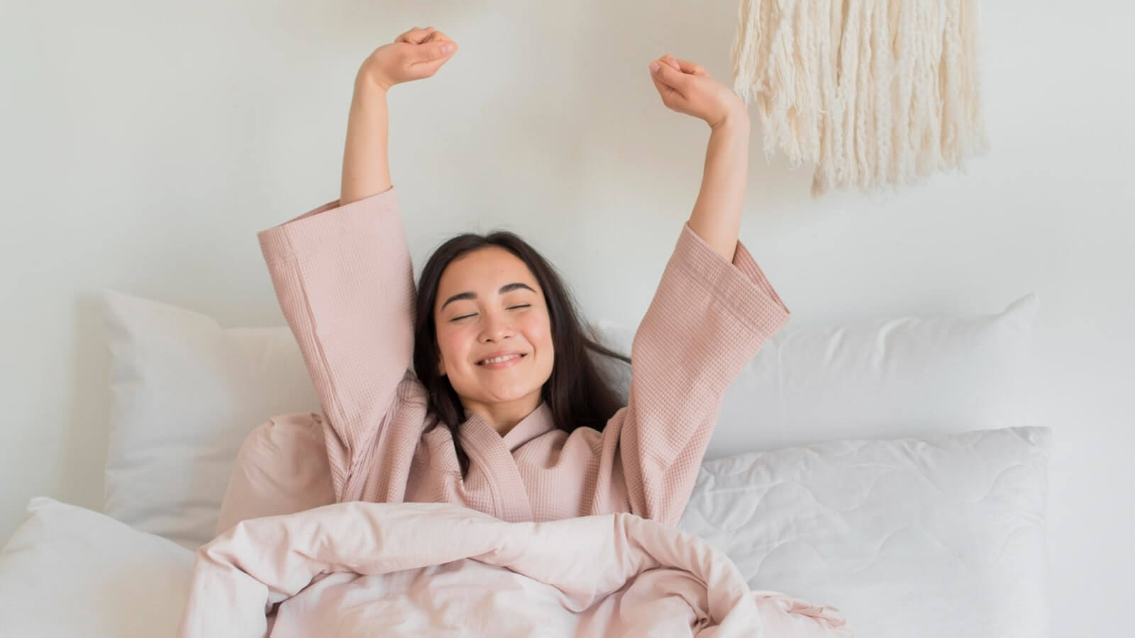 a woman in pajamas stretching her arms in bed