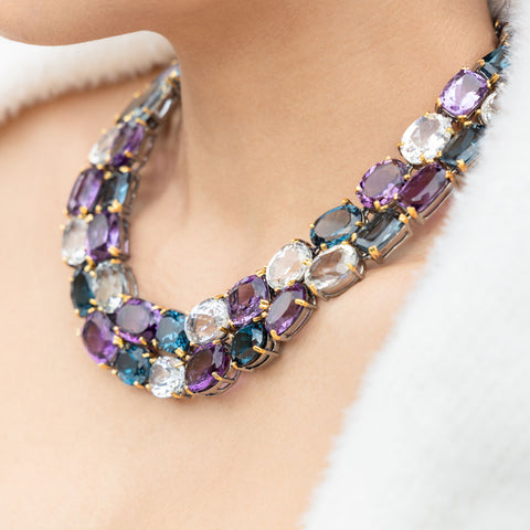 A woman wears and amethyst and aquamarine necklace as part of a custom design jewelry piece.