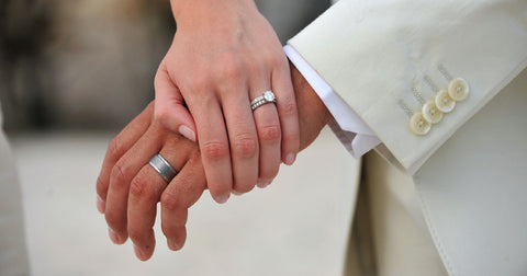 A photo of a man and woman's hands with their matching bridal rings. 