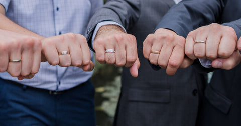 Five men's hands showing off their custom men's wedding bands as part of the bridal rings collection.