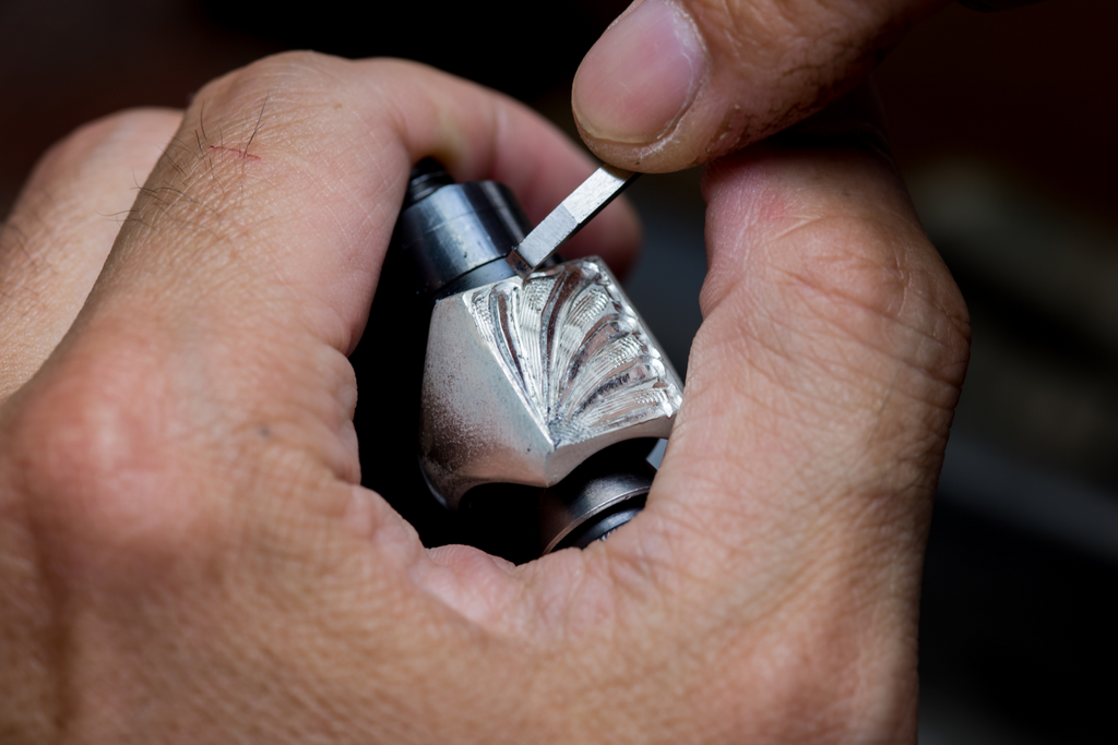 A jeweler hand engraves a men's fine fashion jewelry ring. 
