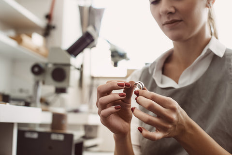 A jeweler inspects and polishes men's wedding rings. 