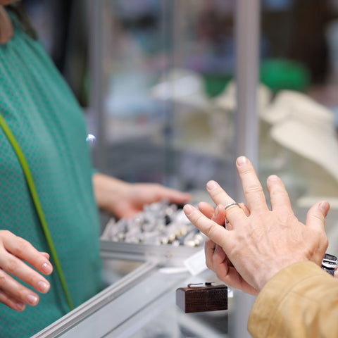 A man tries on a men's wedding band in the jewelry store to ensure a perfect fit.