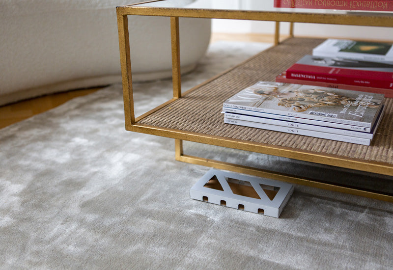 Moth box laid underneath a gold table with a glass top and a brushed grey rug