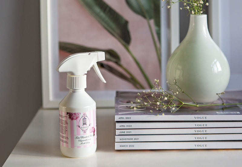 Chrysanthemum moth spray bottle on top of white dresser beside stack of magazines