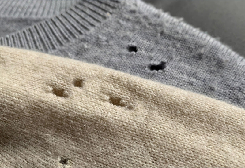 Grey and beige wool jumpers with holes from clothes moths