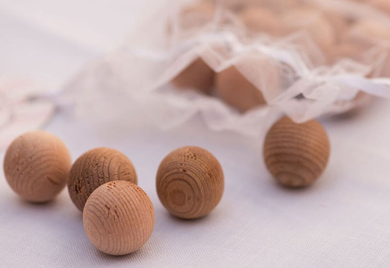 Loose cedarwood moth balls with open fabric bag containing more cedar balls