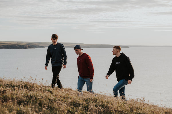 3 people wearing cove clothing walking up hill