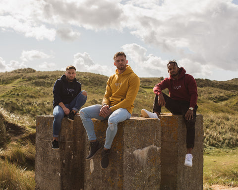 3 boys wearing hoodies sitting on rocks