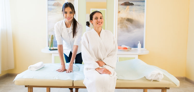 A beauty therapist and a customer in a massage room smiling