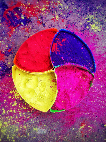 A tray of colourful powder with 4 colours - red, indigo, fushcia and yellow