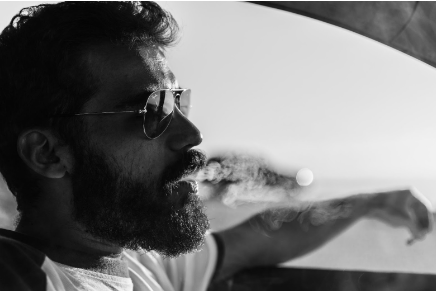 Man with a brown hair and beard in a black and white photo with sunglasses