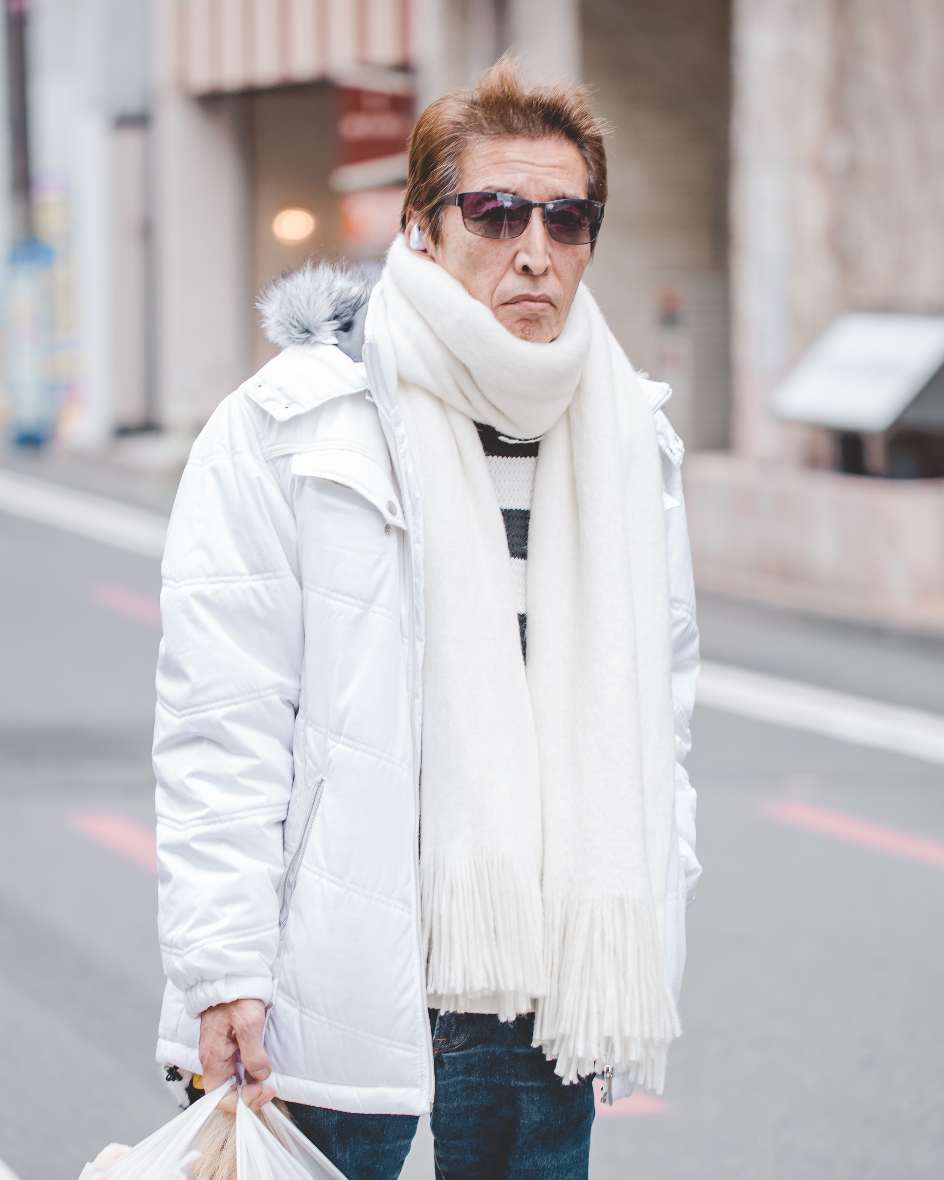 Man in Kyoto wearing the classic loop-styled scarf in a white outfit and jeans.