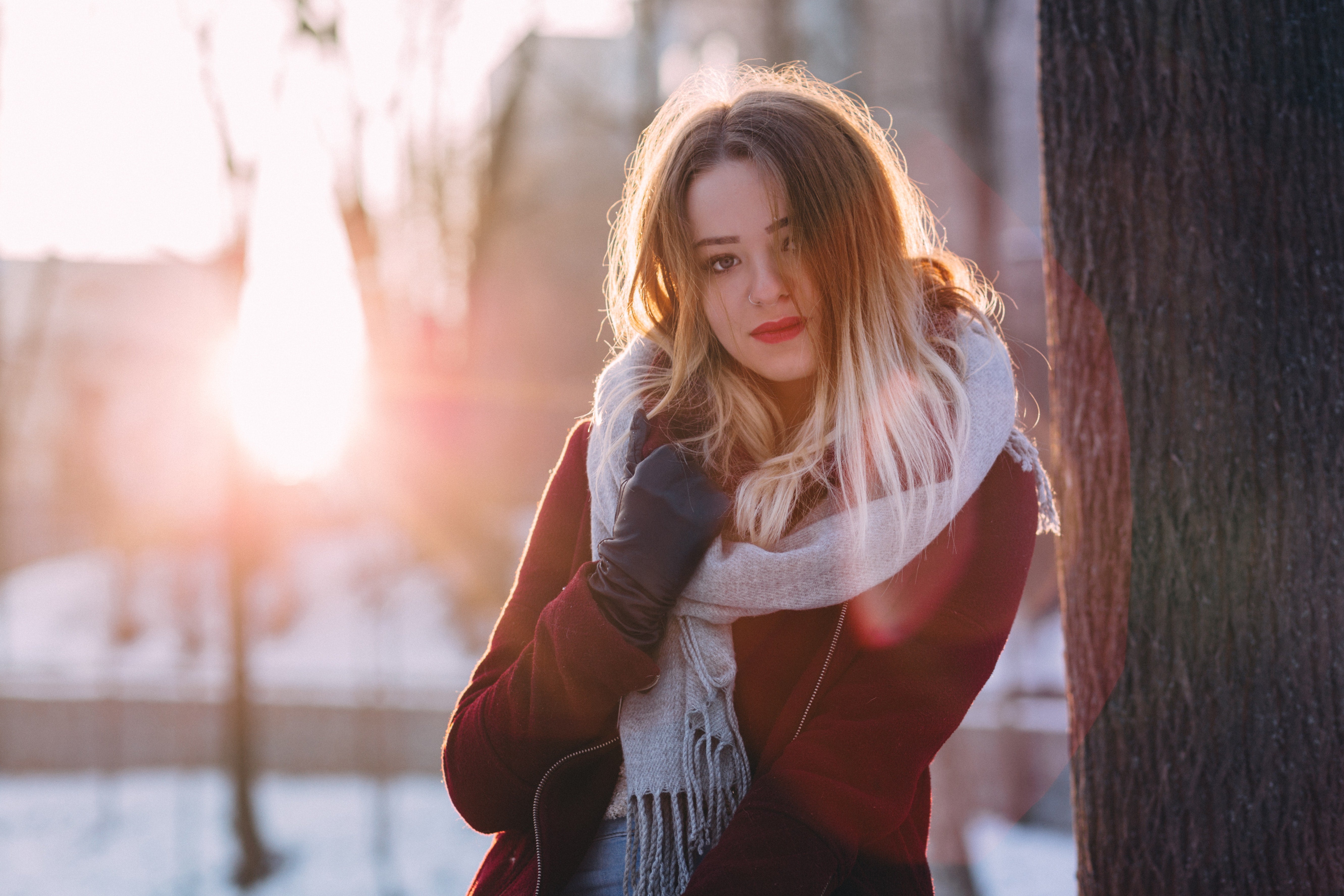Woman wearing a scarf that's grey in the winter while the sun is setting.