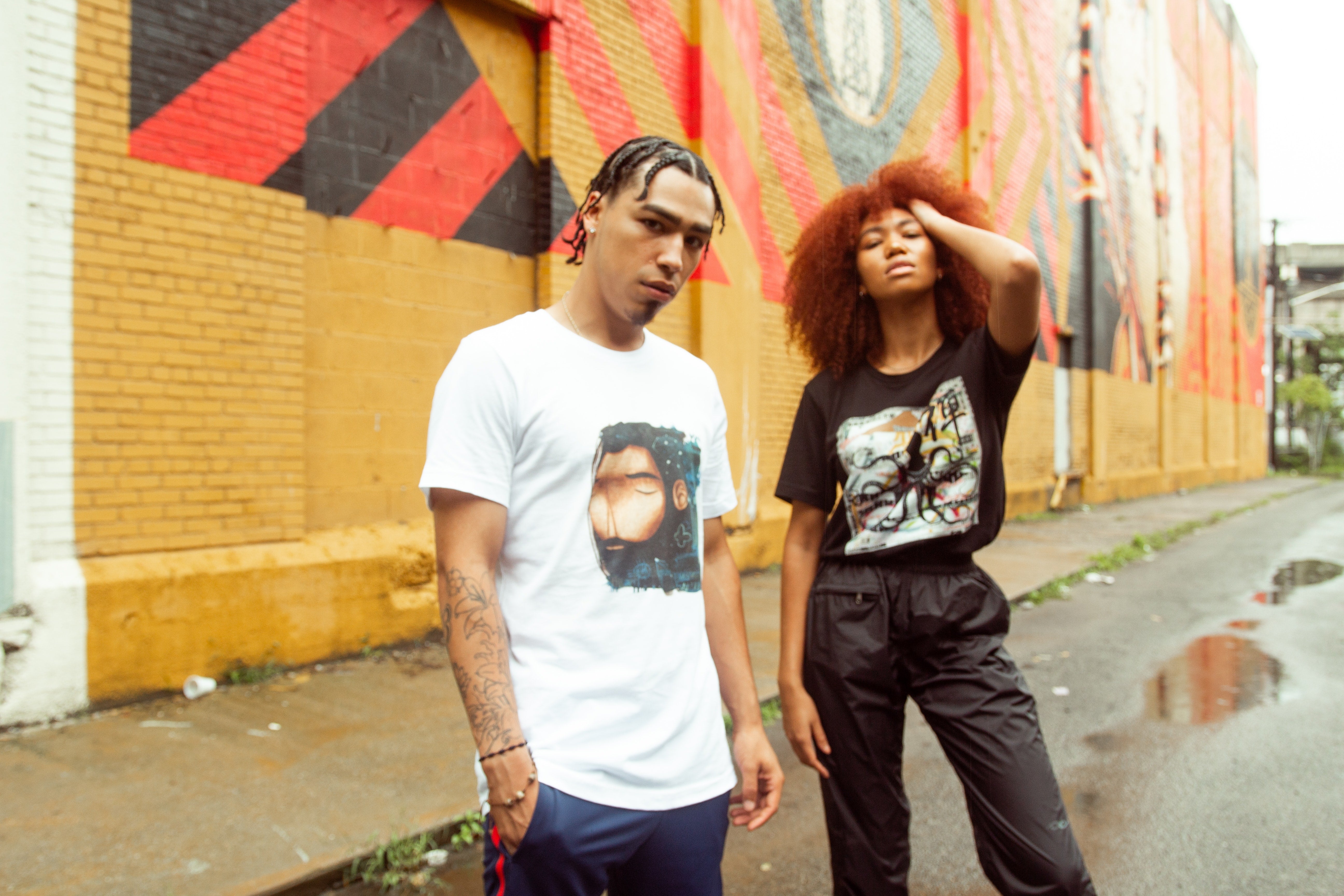 Two models wearing streetwear clothing in an alley