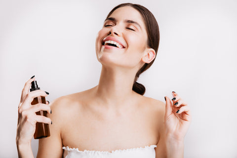 A happy woman applying perfume