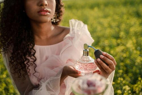 A woman in a pink dress using perfume